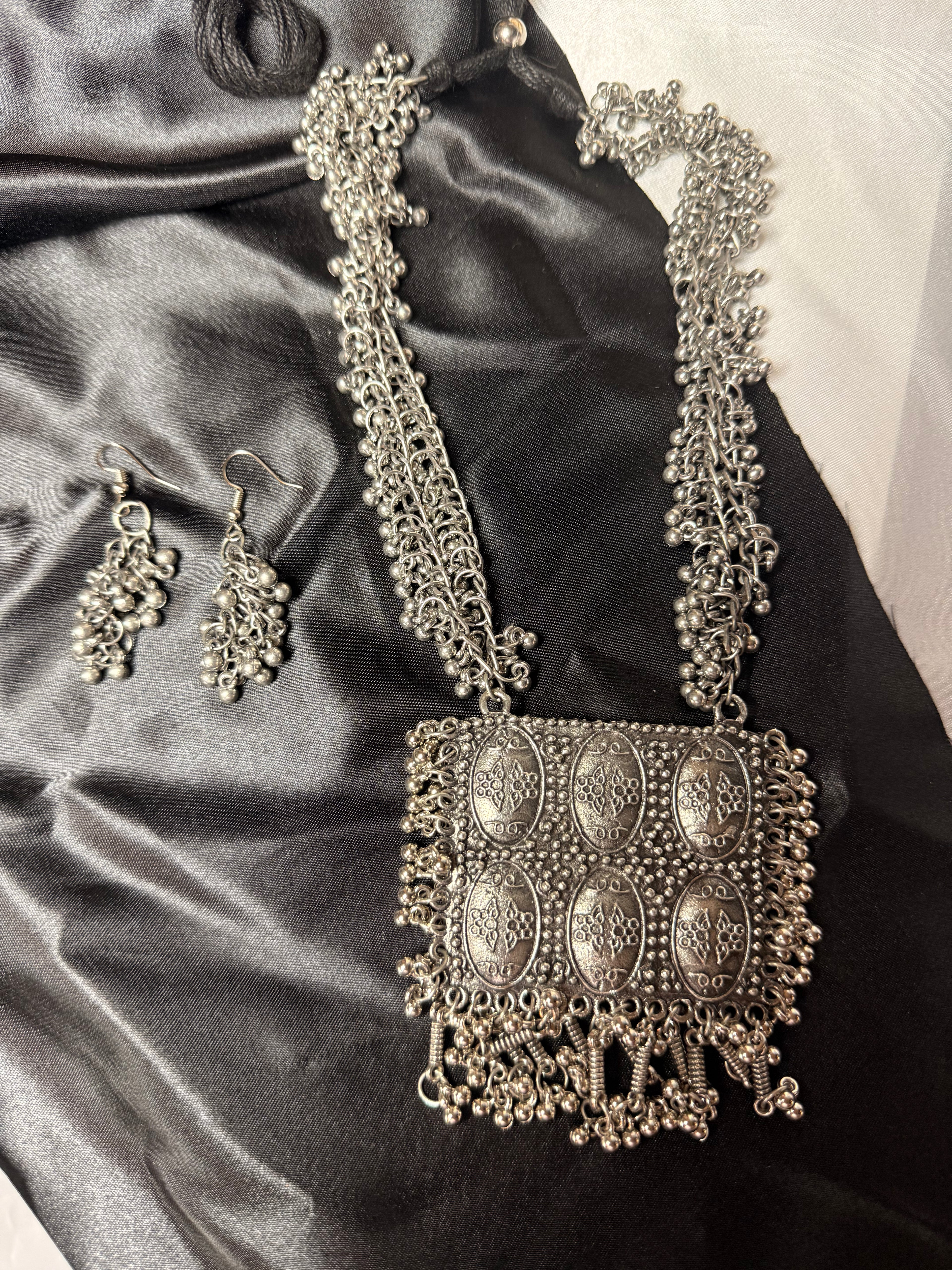 Decorative silver handbag and earrings on a satin surface