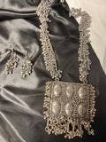 Silver necklace and earrings on a satin surface