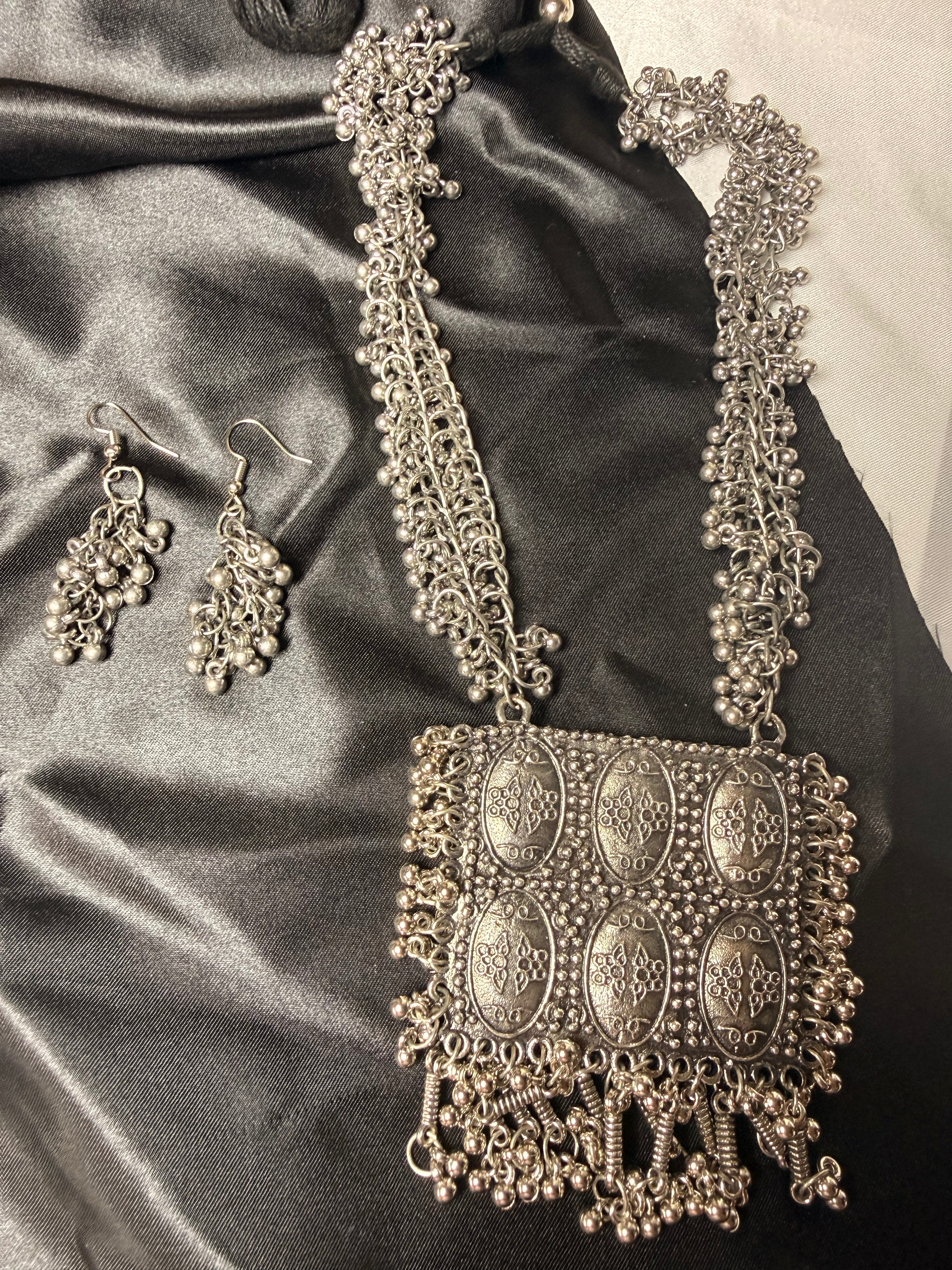 Silver necklace and earrings on a satin surface