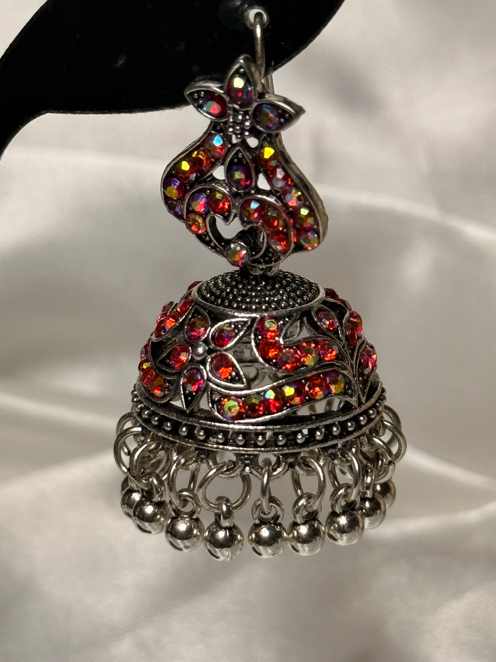 Decorative silver earring with colorful gemstones on a white background
