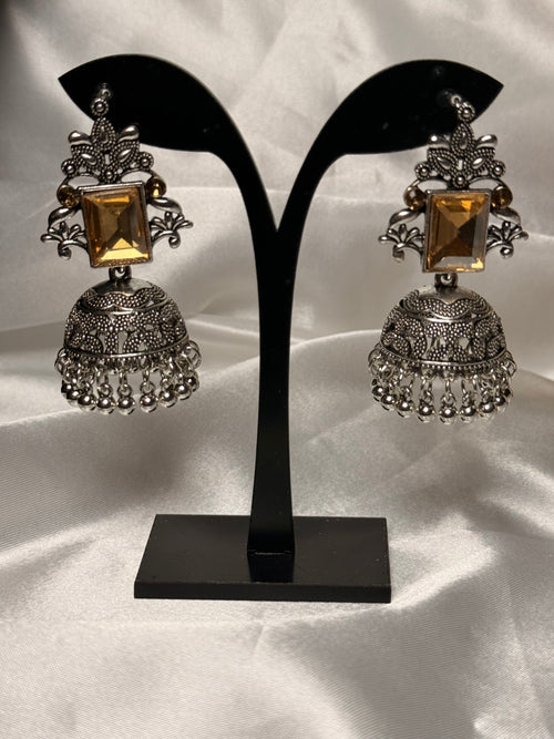 Pair of silver and gold earrings on a black stand against a white background