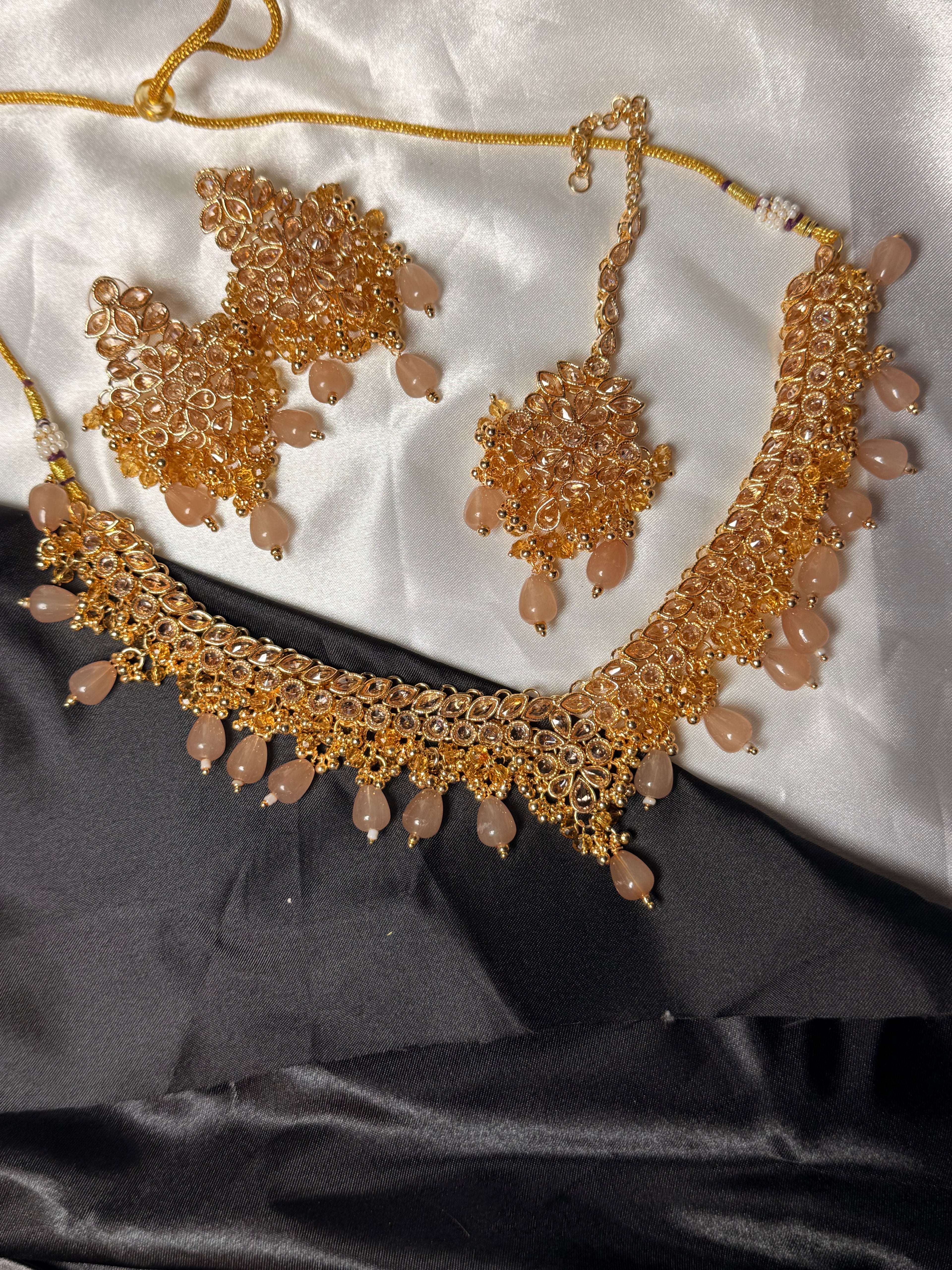 Gold necklace and earrings set on a white and black fabric background