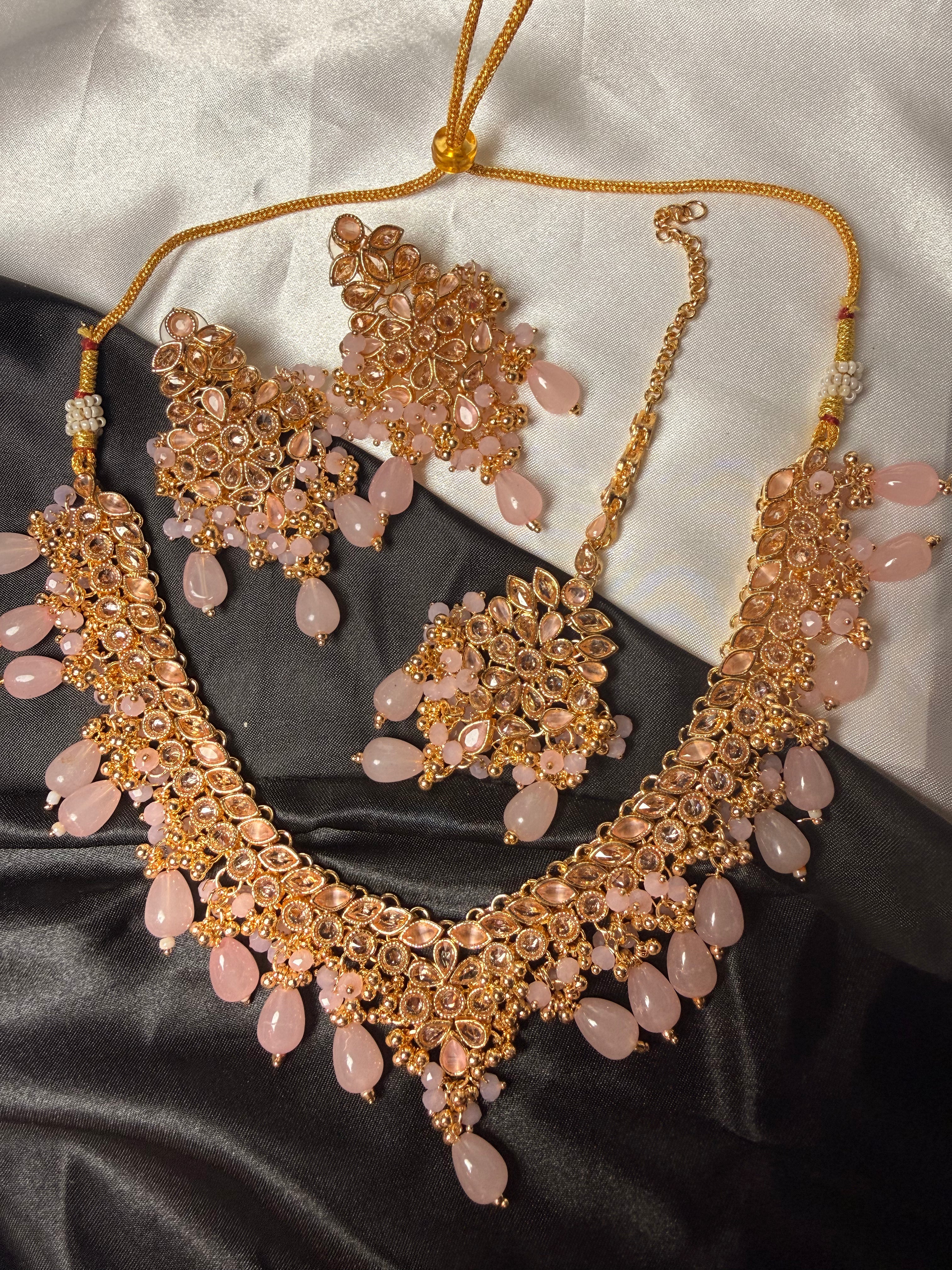 Gold and pink jewelry set on a satin surface