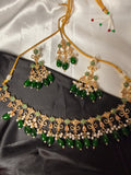Gold and green jewelry set on a satin surface