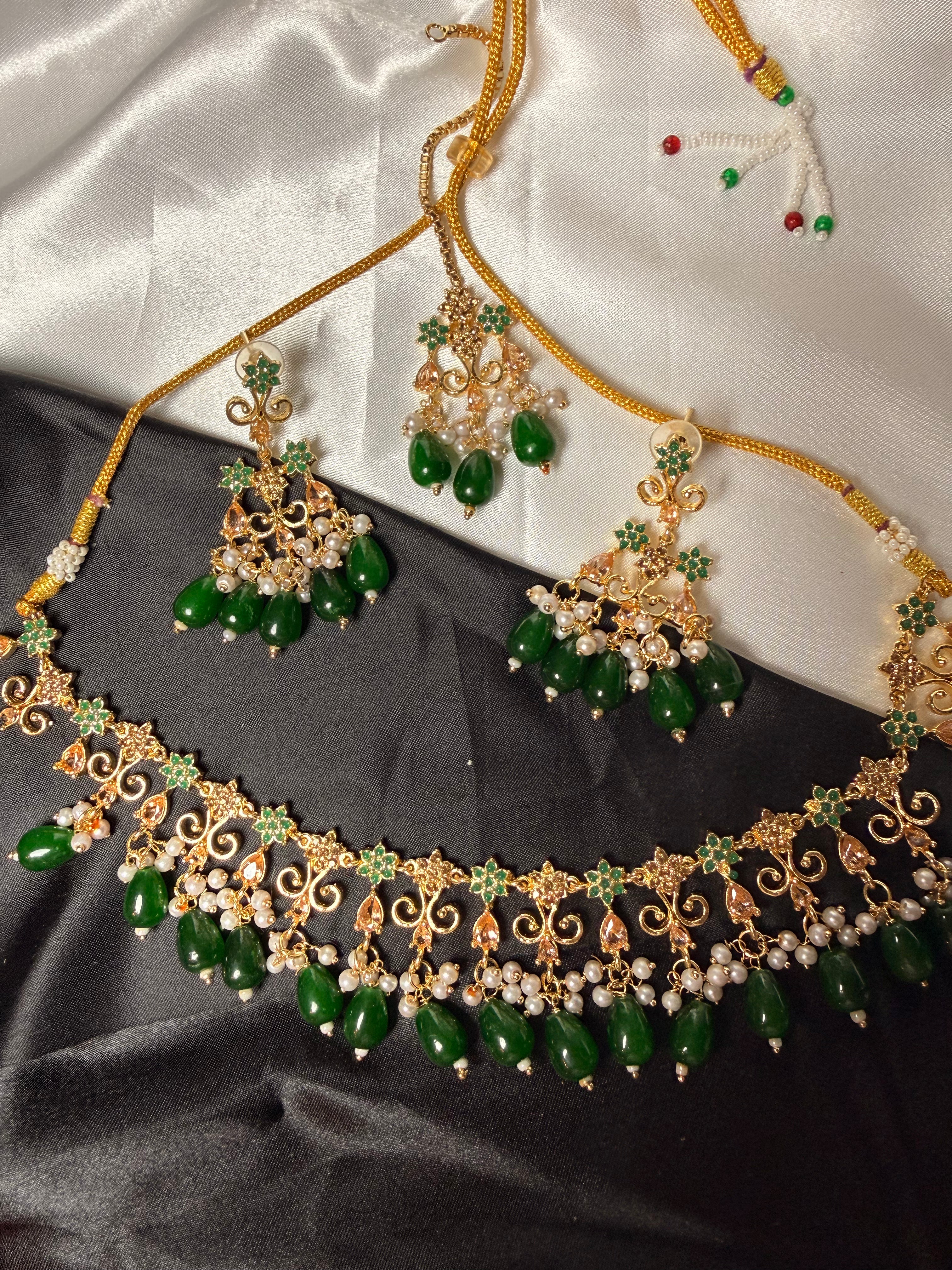 Gold and green jewelry set on a satin surface