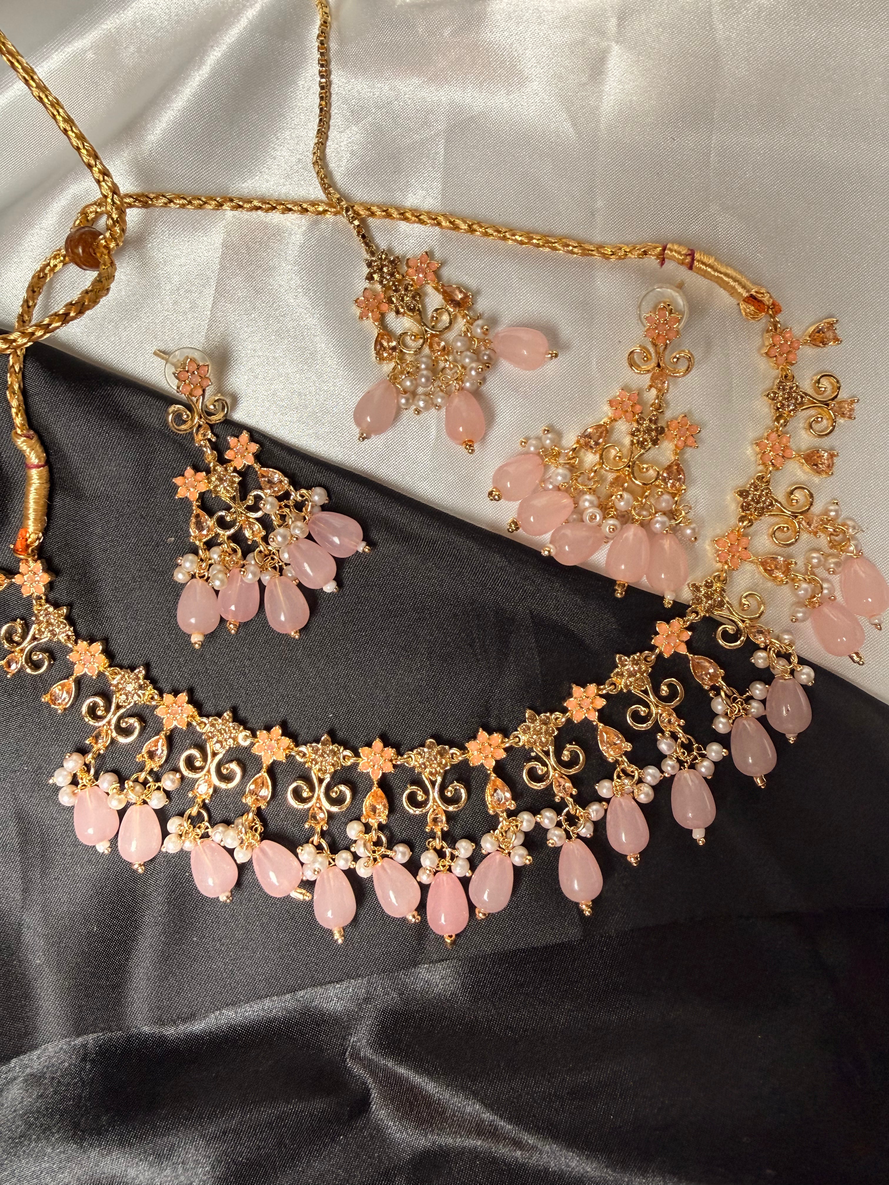 Necklace and earrings with pink stones on a satin surface