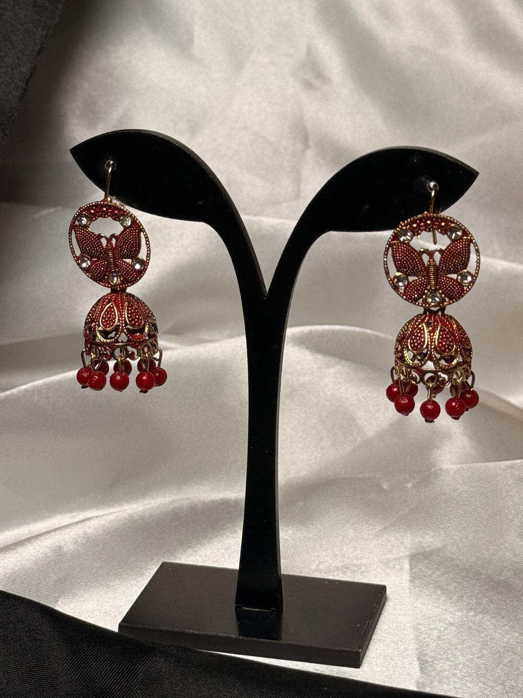 Decorative earrings on a black stand with a white background