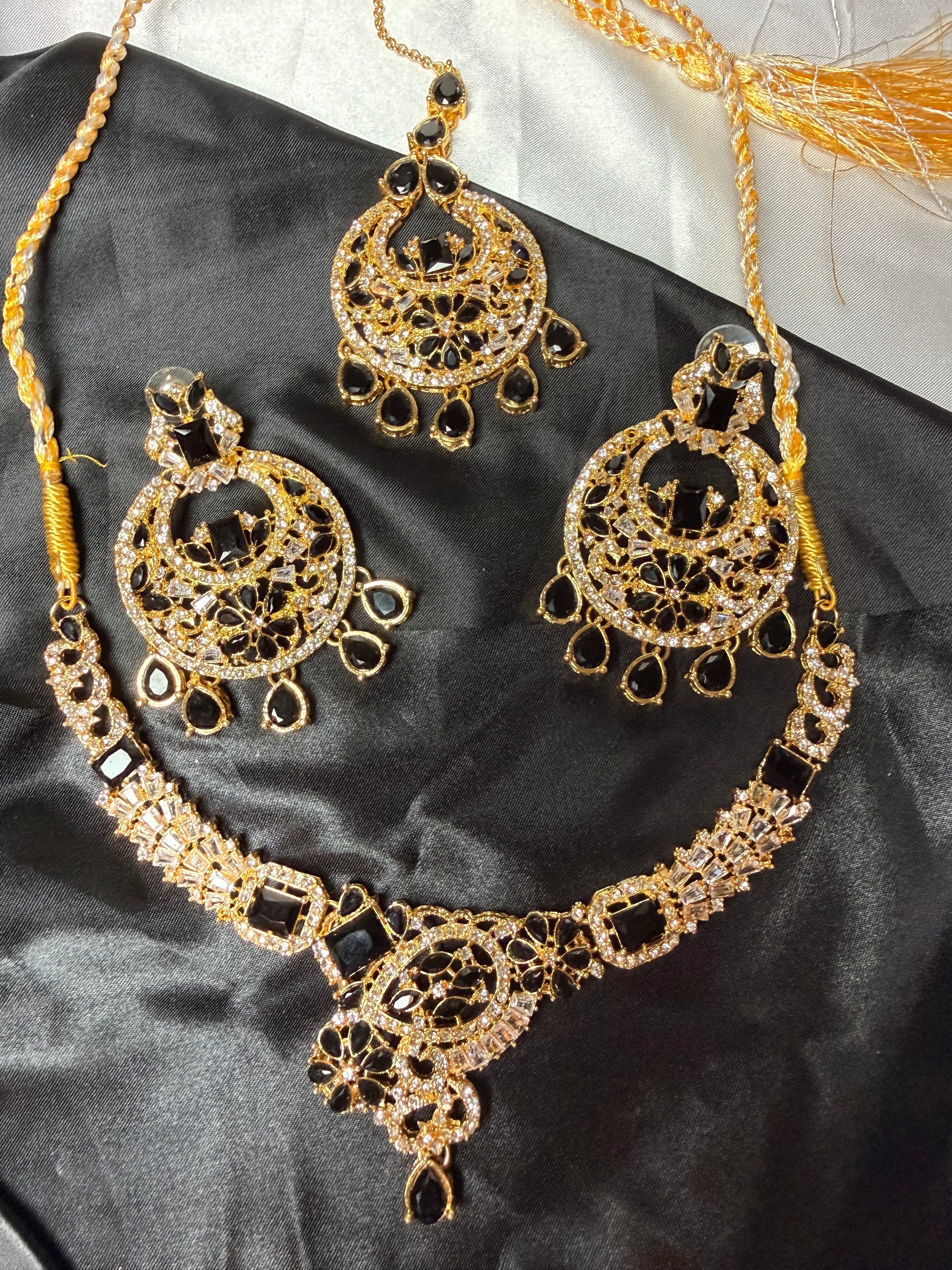 Gold necklace and earrings set on a dark fabric background