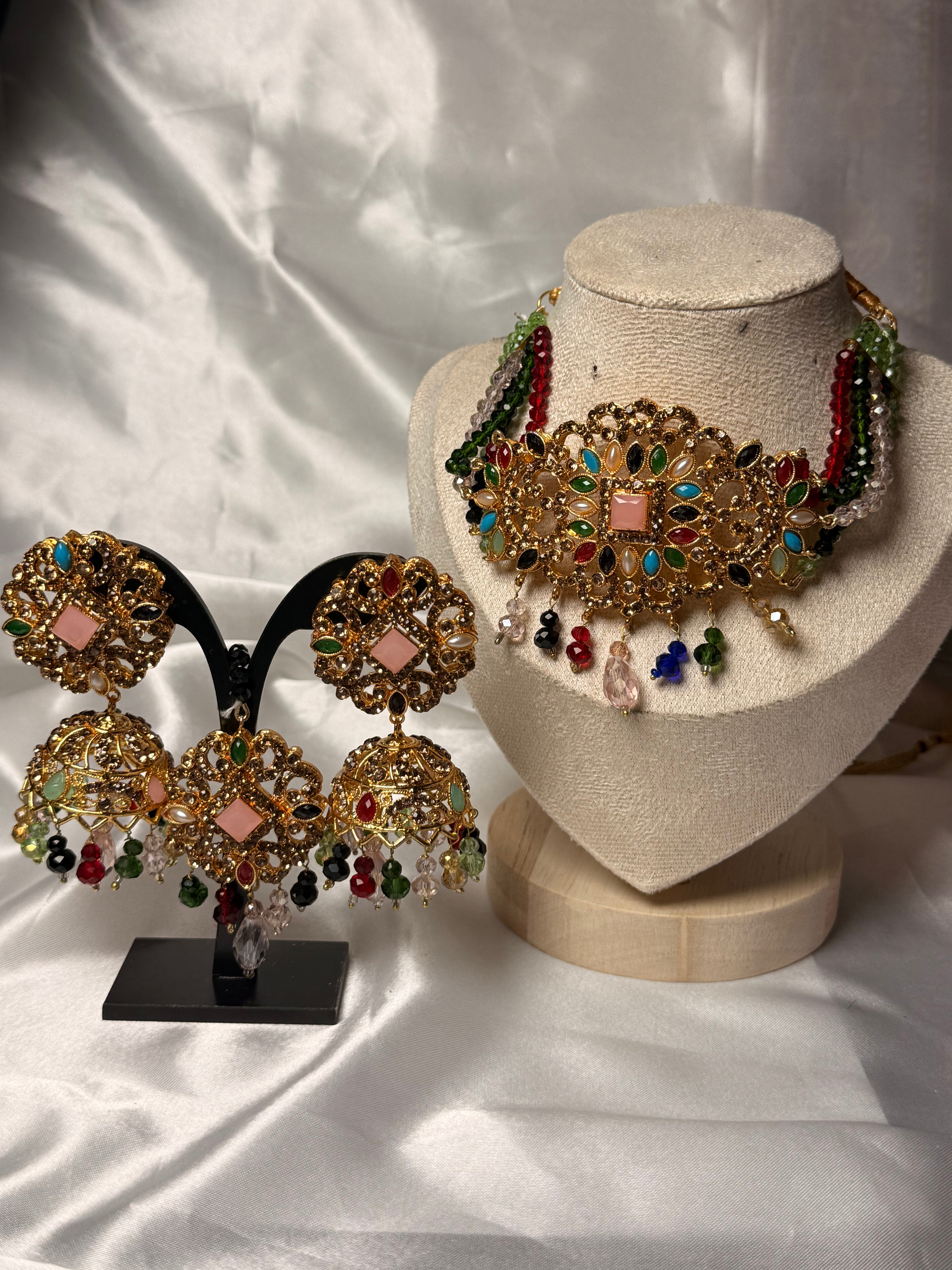 Jewelry set including earrings and a necklace on stands against a light fabric background
