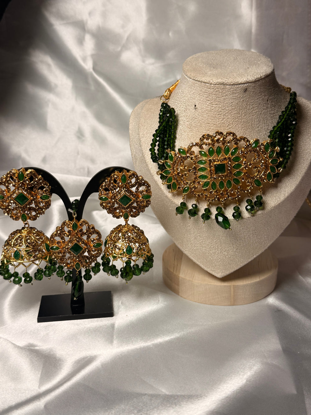 Gold and green jewelry set on a white fabric background
