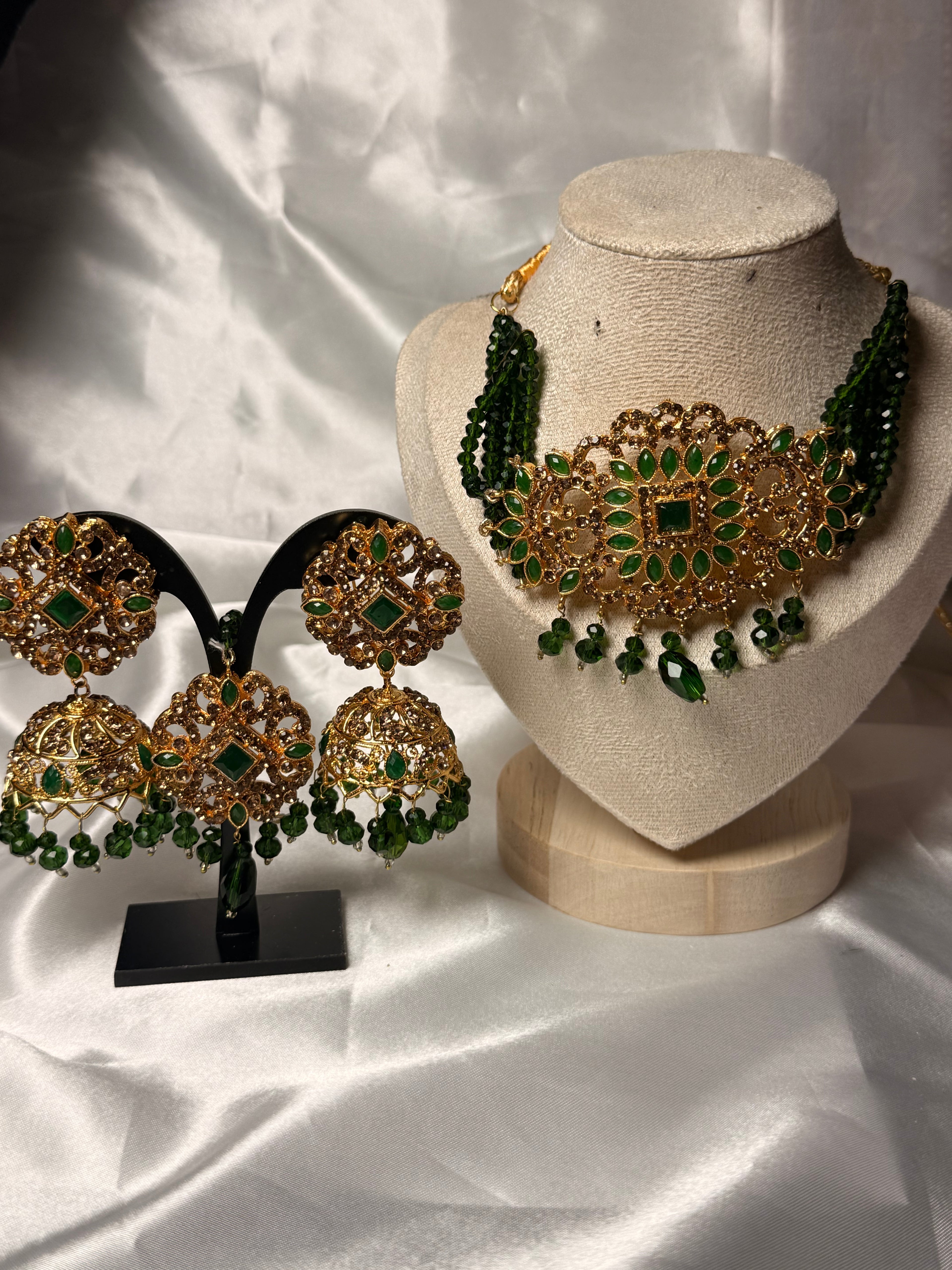 Gold and green jewelry set on a white fabric background