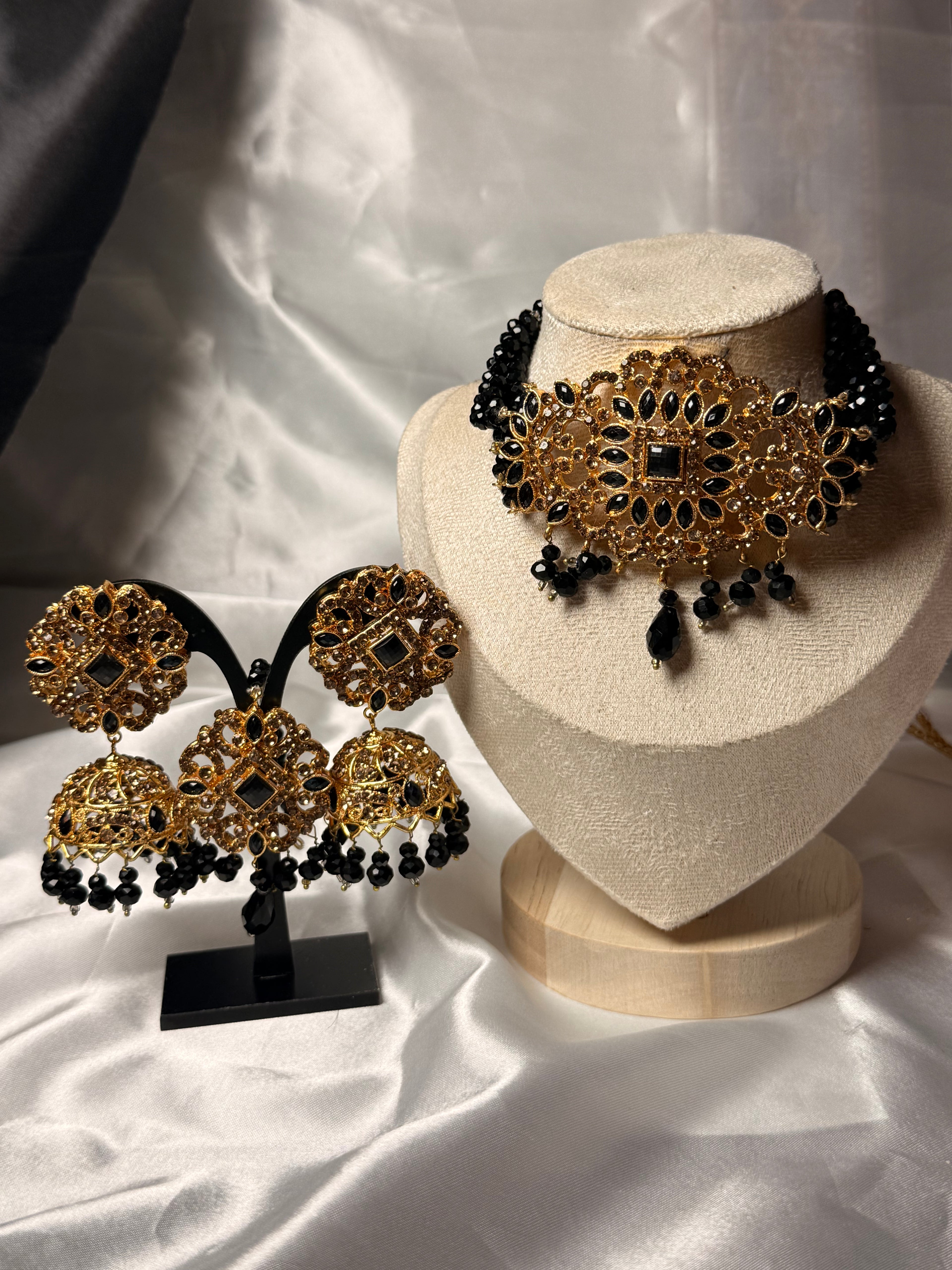 Gold and black jewelry set on a white fabric background